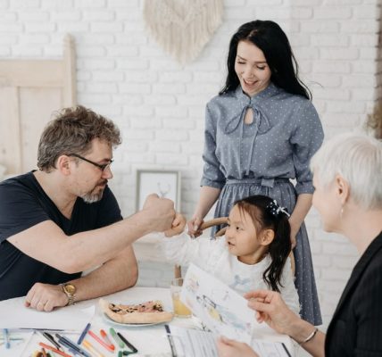 Child with foster parents and a social worker discussing adoption at home.