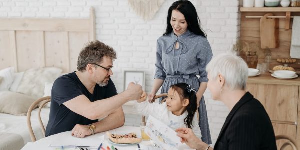 Child with foster parents and a social worker discussing adoption at home.