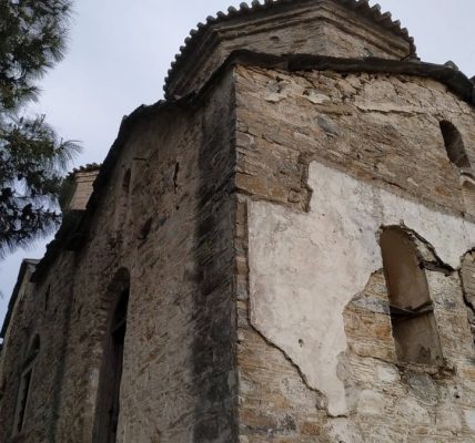 Low-angle view of an ancient stone building in Samos, Greece, surrounded by greenery.