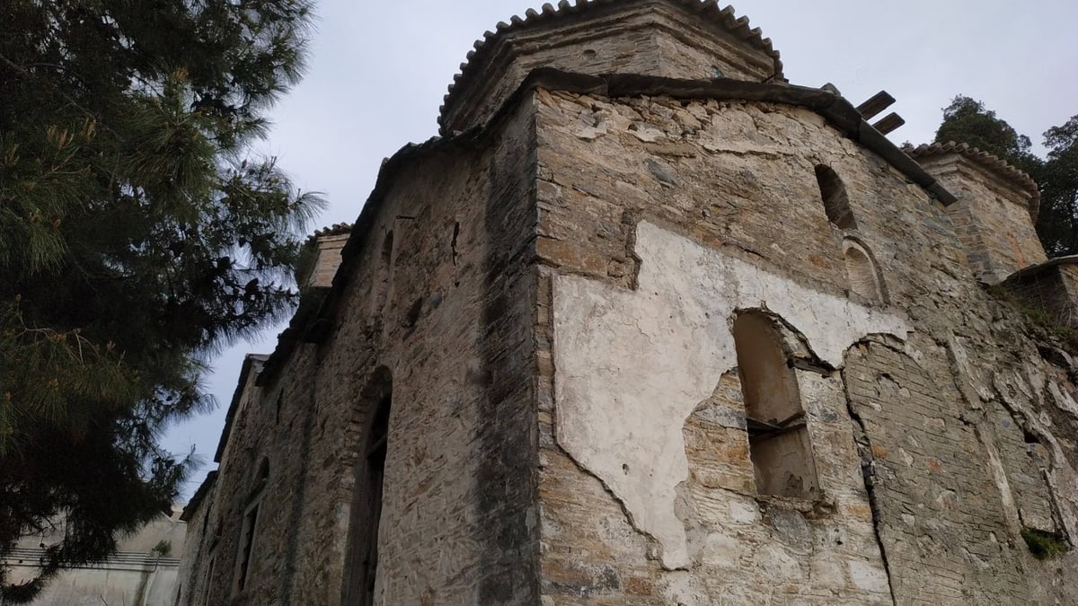 Low-angle view of an ancient stone building in Samos, Greece, surrounded by greenery.